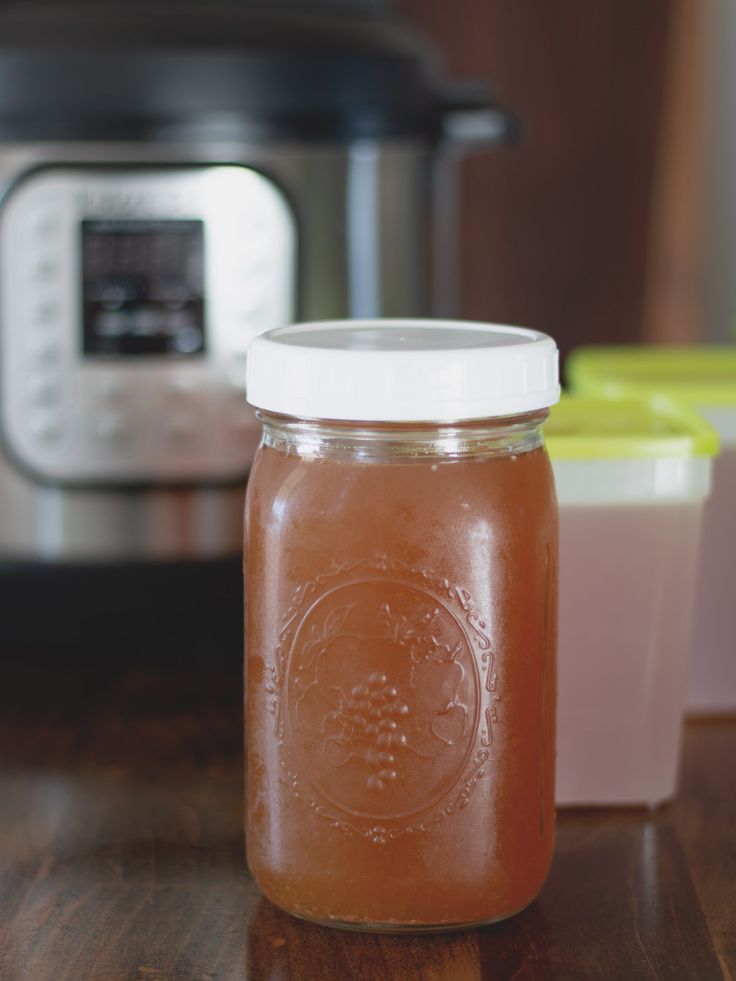 a jar filled with liquid sitting on top of a wooden table next to an instant pot