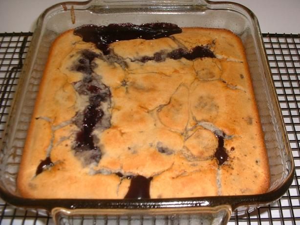 a baked dessert in a baking pan on a cooling rack with chocolate sauce drizzled over the top