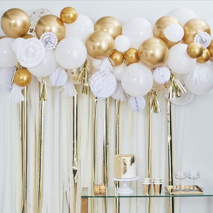 gold and white balloons are hanging from the ceiling