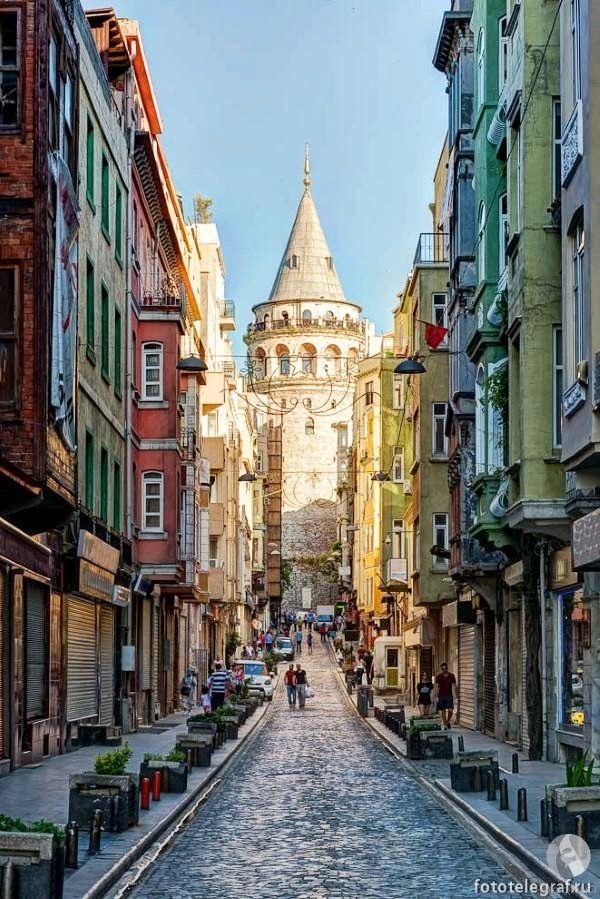 an old city street lined with buildings and people walking on the sidewalk in front of it