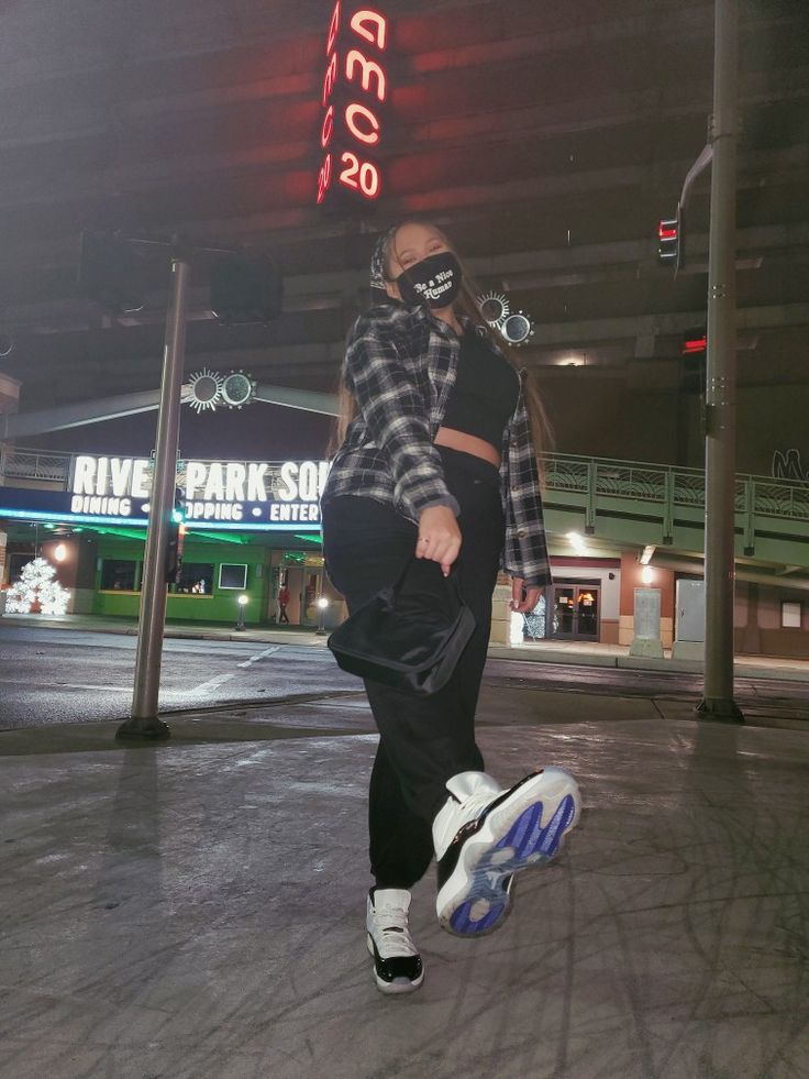 Picture of a women standing by the street, wearing black sweatpants, black crop top, black and white flannel, black mask, and black and white concord 11's. Holding a black purse Outfits With Concord 11s, Concords 11 Outfit Women, Concord 11 Outfit Women, Retro Jordan Outfits Womens, Black And White Jordans Outfit, Flannel Outfits Sweatpants, Jordan 11 Low Outfit Women, Streetwear Outfits Black Women, Black And White Flannel Outfit Aesthetic