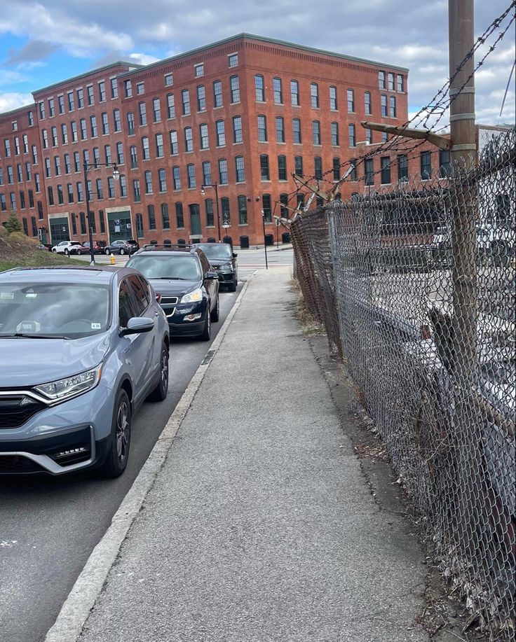 several cars are parked on the side of the road in front of an industrial building