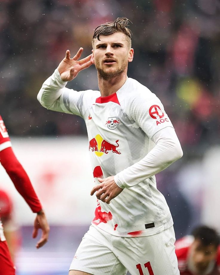 a soccer player with his hand up in the air as he looks at the ball