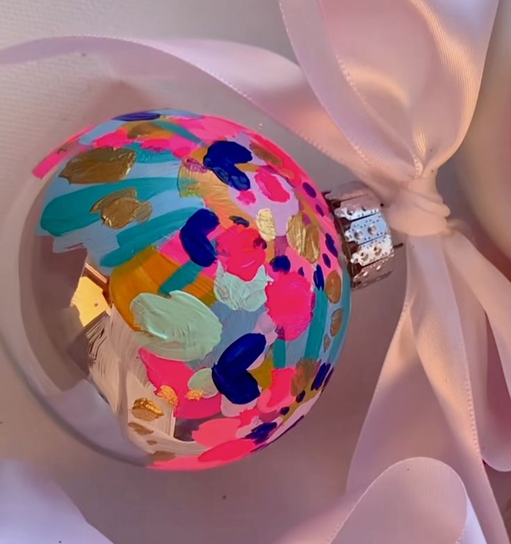 a colorful ornament with a pink ribbon around it