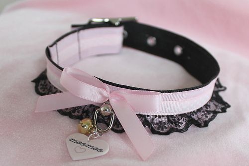 a pink collar with a heart charm attached to it's side and a black ribbon around the collar