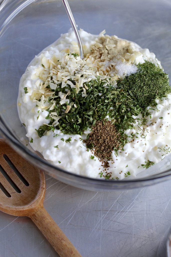 a glass bowl filled with food next to a wooden spoon