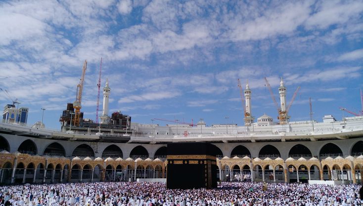 a large group of people standing in front of a building under a cloudy blue sky