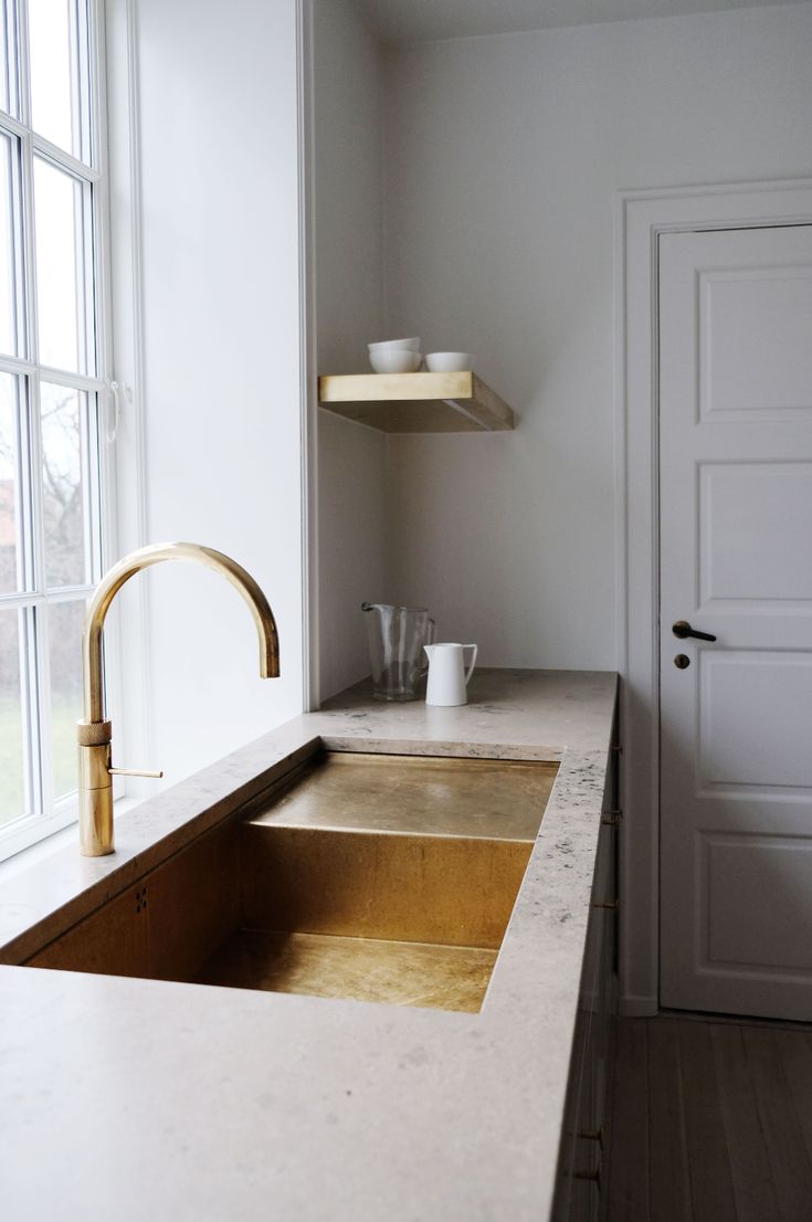 a kitchen sink sitting under a window next to a counter top with a cup on it