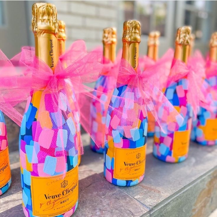 several bottles of champagne are lined up on a table with pink and blue squares around them