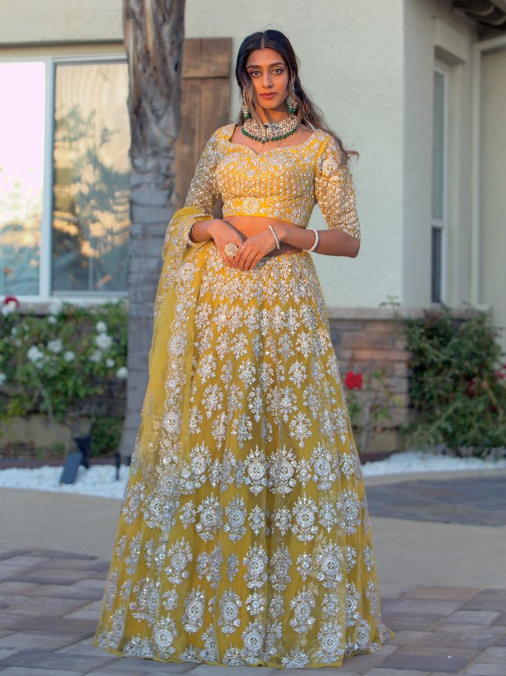 Go all out in this whimsical lehenga, studded with precious mirror, pearl, stone, embroidery work, which is sure to bring out the innate grace and grandeur in you! Color - Chrome Yellow Fabric & Work Style - - Silk blouse: mirror, pearl, stone, embroidery work. - Soft net lehenga: mirror, pearl, stone, embroidery work. - Soft net dupatta: embroidery work. Details - - Assured quality - Wash care instruction: Dry clean only. - Slight variation in color is possible due to digital photography. Yellow Embellished Choli For Eid, Eid Embellished Yellow Choli, Eid Yellow Embellished Choli, Yellow Lehenga With Intricate Embroidery, Yellow Embellished Anarkali Set For Diwali, Yellow Embellished Dupatta For Diwali, Embellished Yellow Dupatta For Diwali, Anarkali Sets With Pearl Embroidery For Reception, Embellished Yellow Lehenga For Diwali