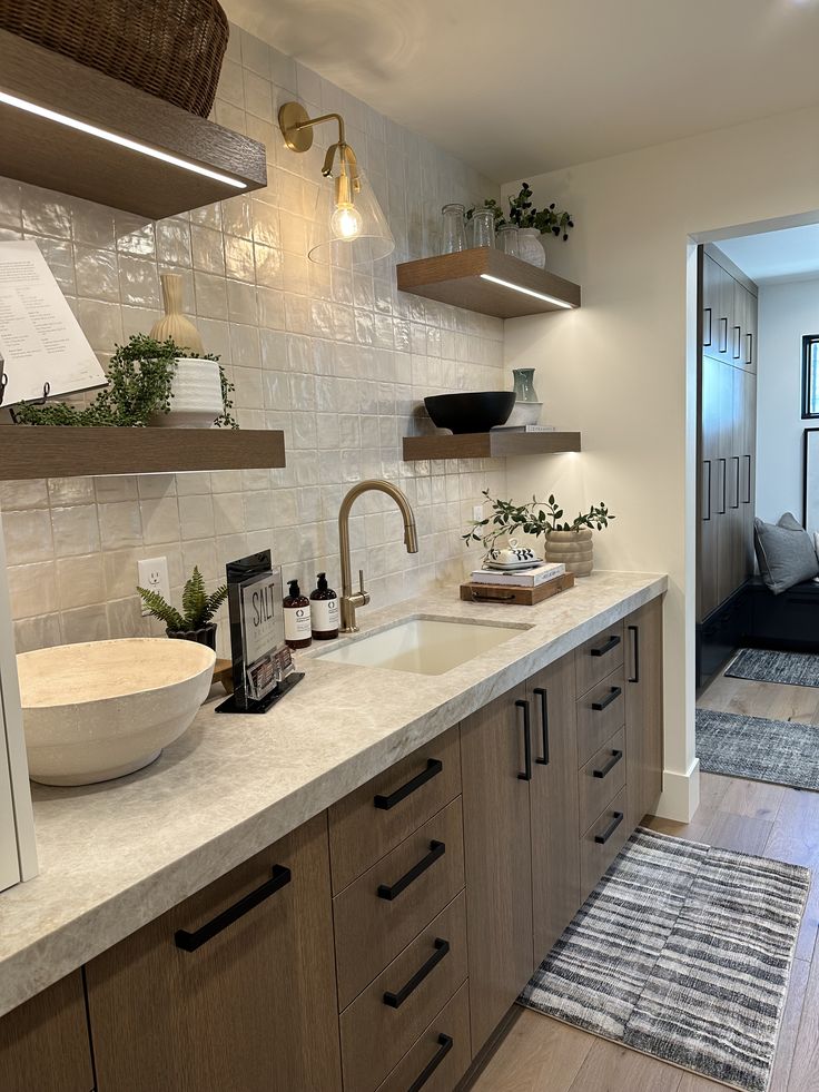 a kitchen with a sink, counter top and shelves on the wall next to it