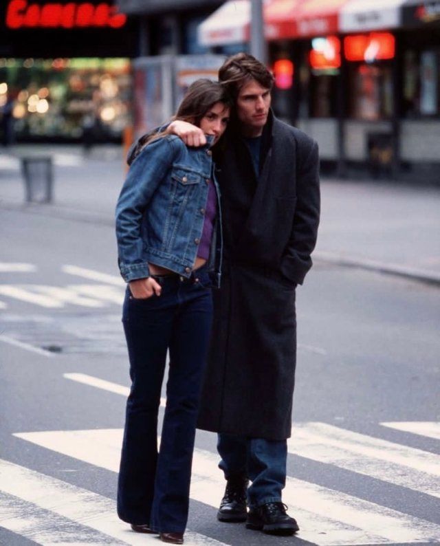 a man and woman standing on the street in front of a crosswalk with their arms around each other