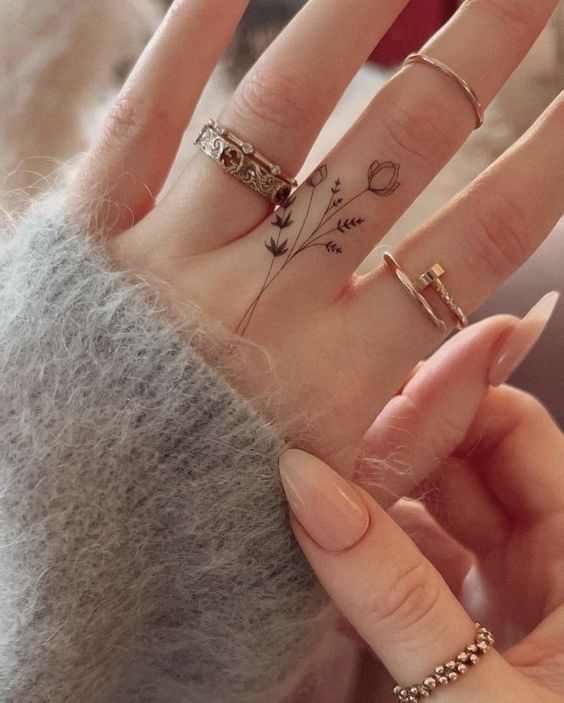 a woman's hand with four different rings on it and two fingers that have flowers painted on them