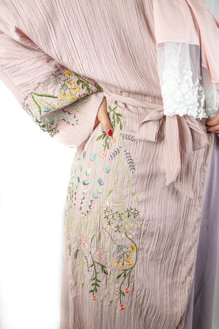 This Dusty Pink Floral Embroidered Abaya is perfect for any modern fashionista. Showcasing a beautiful faded pink with delicate embroidered floral detail, this Abaya will make you stand out in any occasion. This eye-catching mauve abaya is made of high quality textured fabric with floral embroidery along the sleeves and along the side of the abaya. The Floral Embroidered Abaya features buttons and a belt, providing you with the versatile options to wear it open or closed, tied or loose. Matching Floral Embroidered Abaya For Eid Wedding, Pink Floral Embroidered Kaftan For Wedding, Pink Floral Embroidered Kaftan, Bohemian Pink Resham Embroidered Kaftan, Bohemian Pink Resham Embroidery Kaftan, Elegant Floral Embroidered Kaftan For Spring, Wedding Abaya With Floral Embroidery, Bohemian Pink Kaftan With Resham Embroidery, Elegant Spring Kaftan With Floral Embroidery