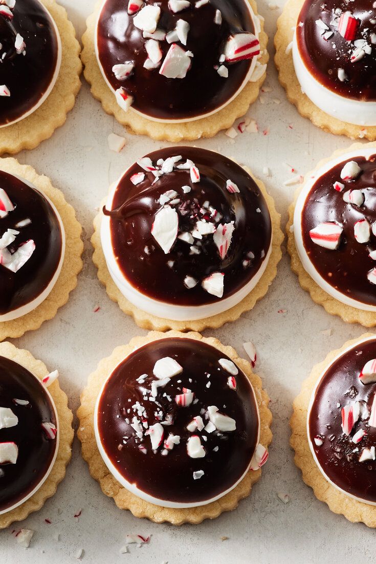 chocolate covered cookies with candy canes and white frosting on top, lined up in rows