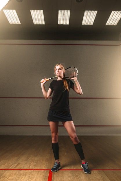 a woman is holding a tennis racket in an empty room