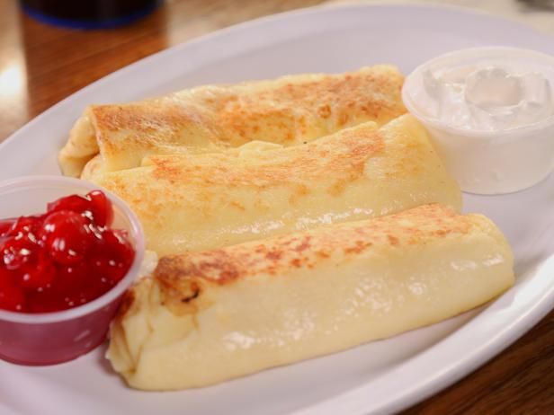 two quesadillas on a white plate with ketchup and sour cream