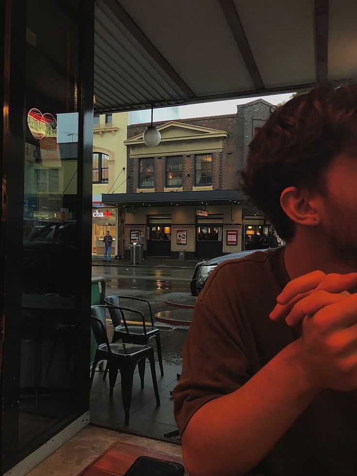 a man standing in front of a window with his hands clasped to his chest and looking at the camera