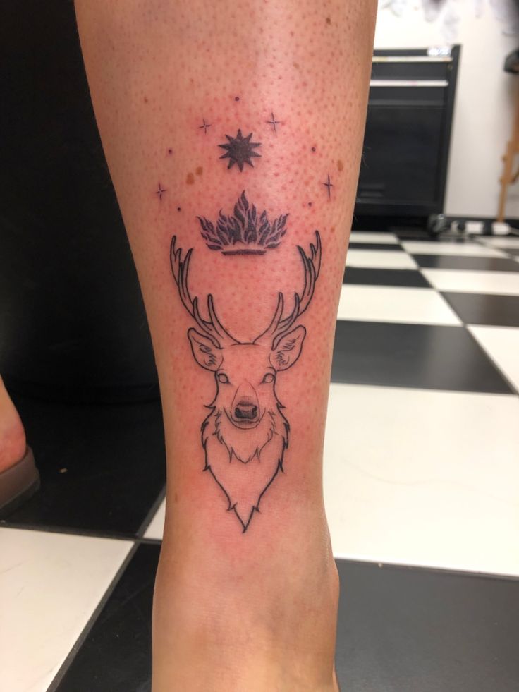 a tattoo on the leg of a person with a deer's head and stars