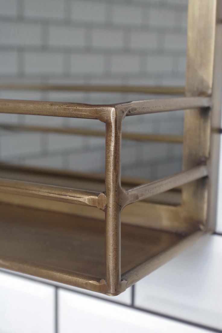 a close up of a metal shelf against a white tile wall