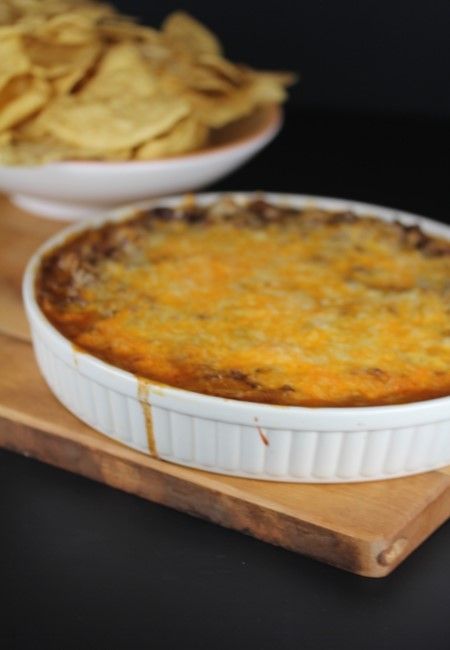 a casserole dish with tortilla chips on a cutting board next to it