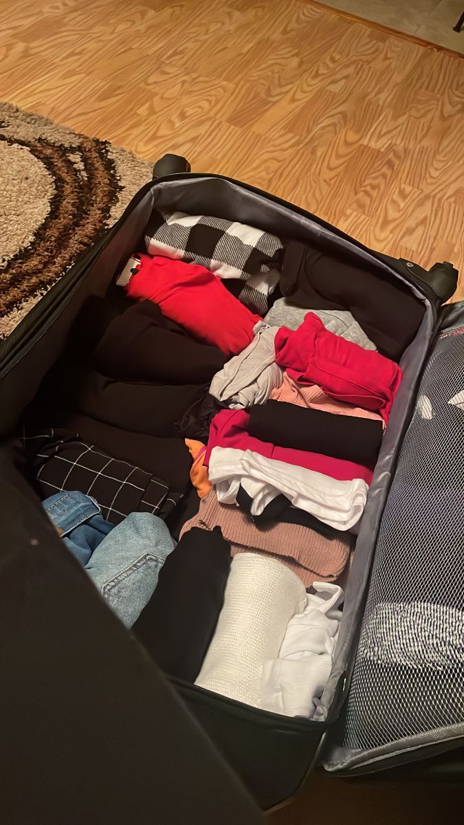 an open suitcase with clothes in it on the floor