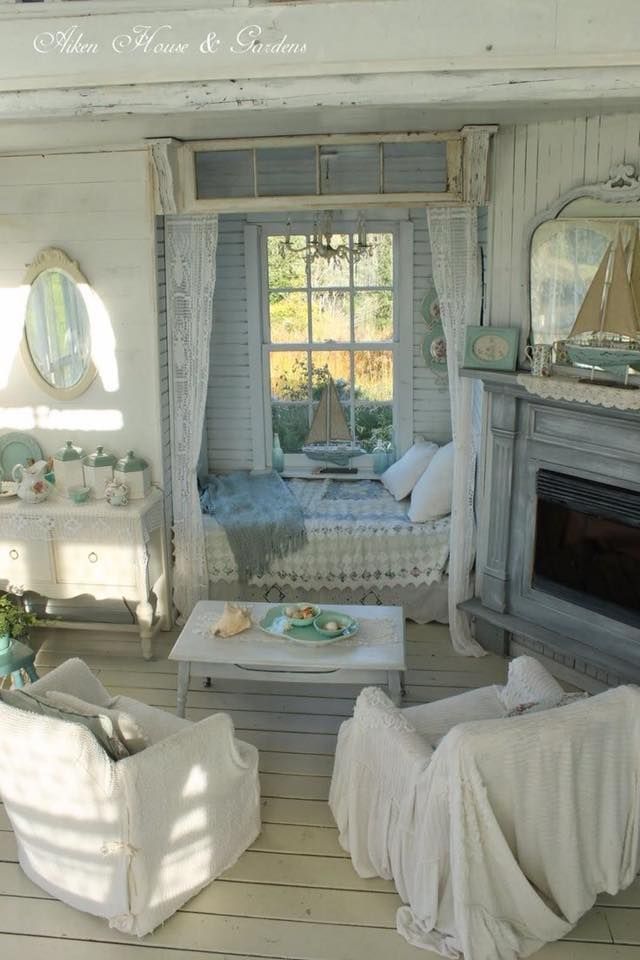 a living room filled with furniture and a fire place next to a window covered in curtains