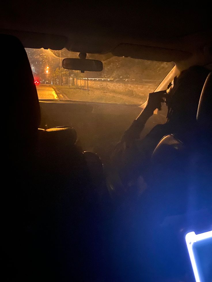 the interior of a car at night with headlights shining on the dashboard and people sitting in the passenger seat