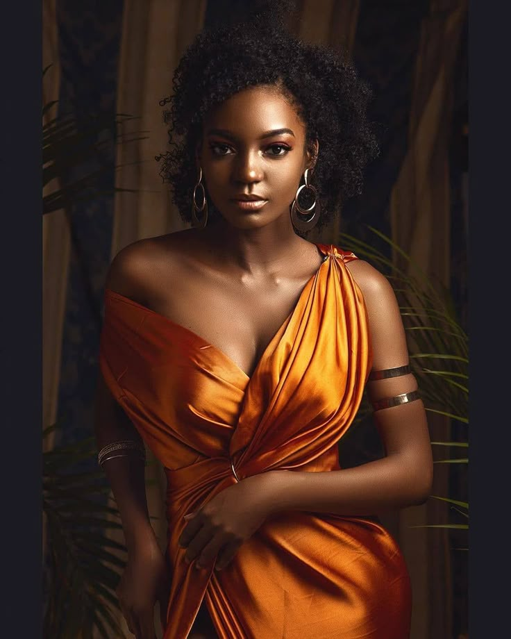 a woman in an orange dress is posing for a photo with her hands on her hips