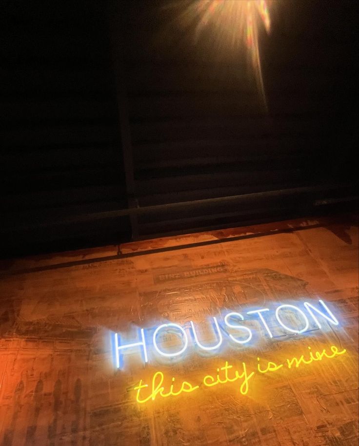 a neon sign that reads houston this city is mine on the floor in front of a building