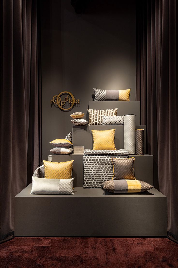 a display case filled with lots of yellow and grey pillows on top of a red carpet