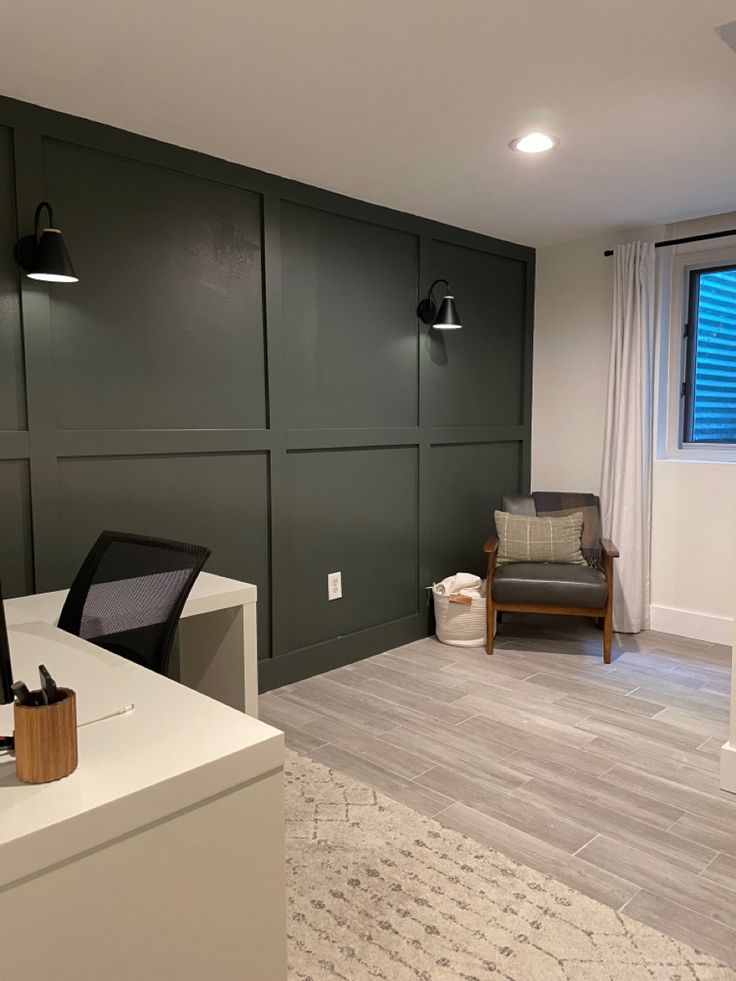 an office with green walls and white furniture in the corner, next to a window