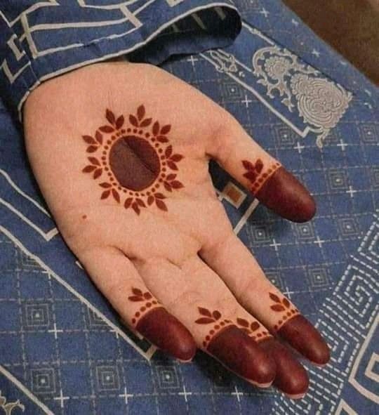 a woman's hand with henna on it and an orange circle painted on the palm