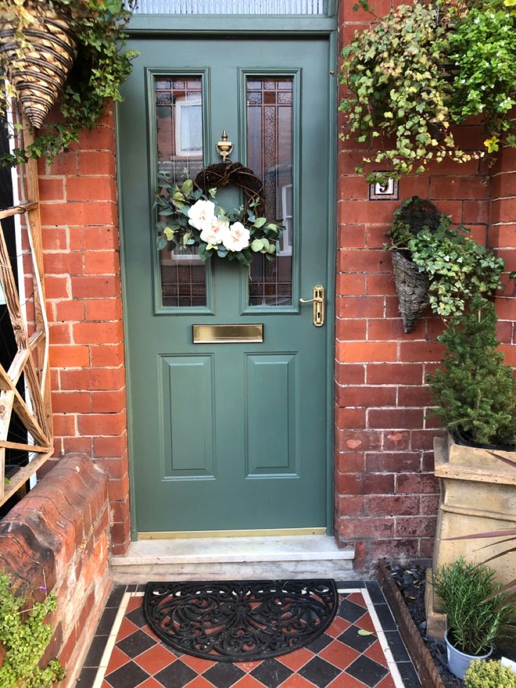 a green front door with a wreath on it and potted plants in the background