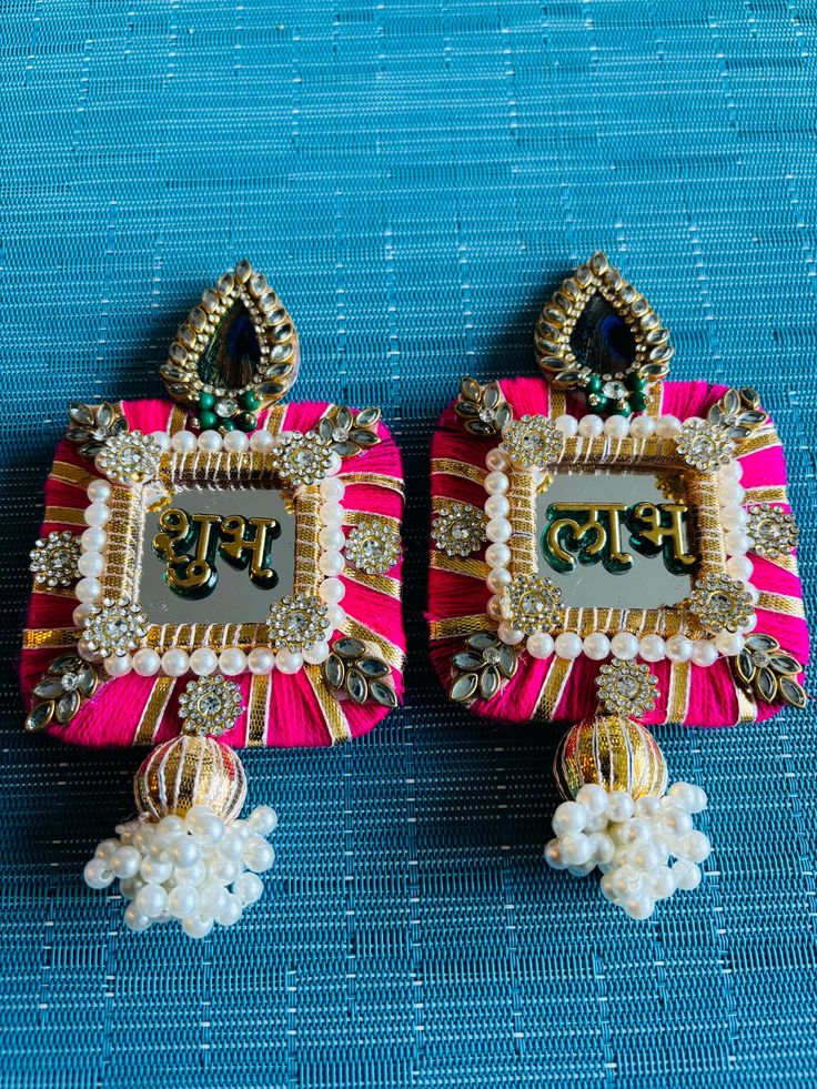 A shubh Labh latkan pair made from beads / motis This beautiful set includes one "Shubh" and one "Labh" hanging, perfect for adding elegance to your home or business.  The Shubh Labh symbol is a combination of two Sanskrit words: "Shubh" meaning auspicious, and "Labh" meaning gain or profit. It is believed to bring good luck and prosperity to the home or office where it is displayed. Dimensions: Length is 15 cm approx. *The Color might be slightly different due to photographic lighting. *Handmad Traditional Luxury Chandbalis With Latkans, Handmade Multicolor Sets For Celebration, Multicolor Navratri Sets With Latkans, Multicolor Sets With Latkans For Navratri, Festive Diwali Sets With Latkans, Handmade Multicolor Sets For Diwali, Traditional Set With Mirror Work, Traditional Sets With Mirror Work For Gift, Traditional Sets With Mirror Work As Gift