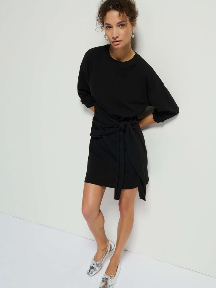 This no-fuss drop-shoulder wrap dress is just what you've been looking for. A relaxed fit crew neck with a contrast neckband, shirring at the waist, and a tie to cinch in as much or as little as you want. Complete the look with your favorite knee-highs and prepare to turn some heads. (This one comes in Jet Black.) | Gloria Dress in Jet Black | Ethical Essentials Black Casual Dress With Tie Fastening, Chic Loungewear Dress With Tie Waist, Chic Dresses With Relaxed Fit And Crew Neck, Chic Crew Neck Dress With Relaxed Fit, Chic Crew Neck Loungewear Dress, Chic Relaxed Fit Dress With Crew Neck, Relaxed Fit Dresses With Tie Waist For Work, Chic Crew Neck Dress For Daywear, Casual Loungewear Dresses With Tie Waist