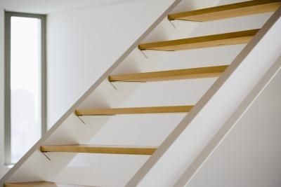 a white staircase with wooden handrails in an empty room