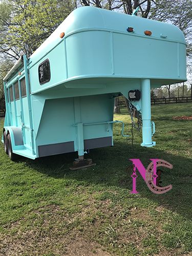 a blue horse trailer parked on top of a lush green field