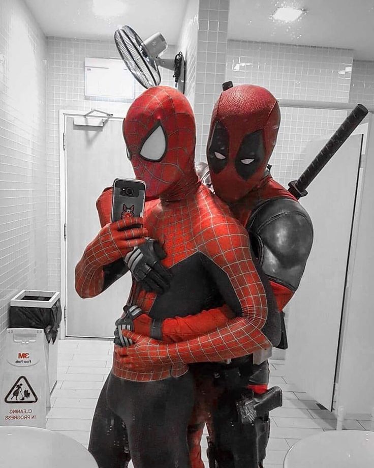 two people dressed as spider - man and deadpool are standing in the bathroom with their arms around each other