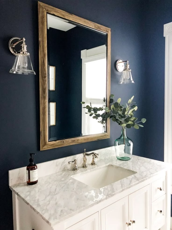 a bathroom with blue walls and marble counter tops, white cabinets and a large mirror on the wall