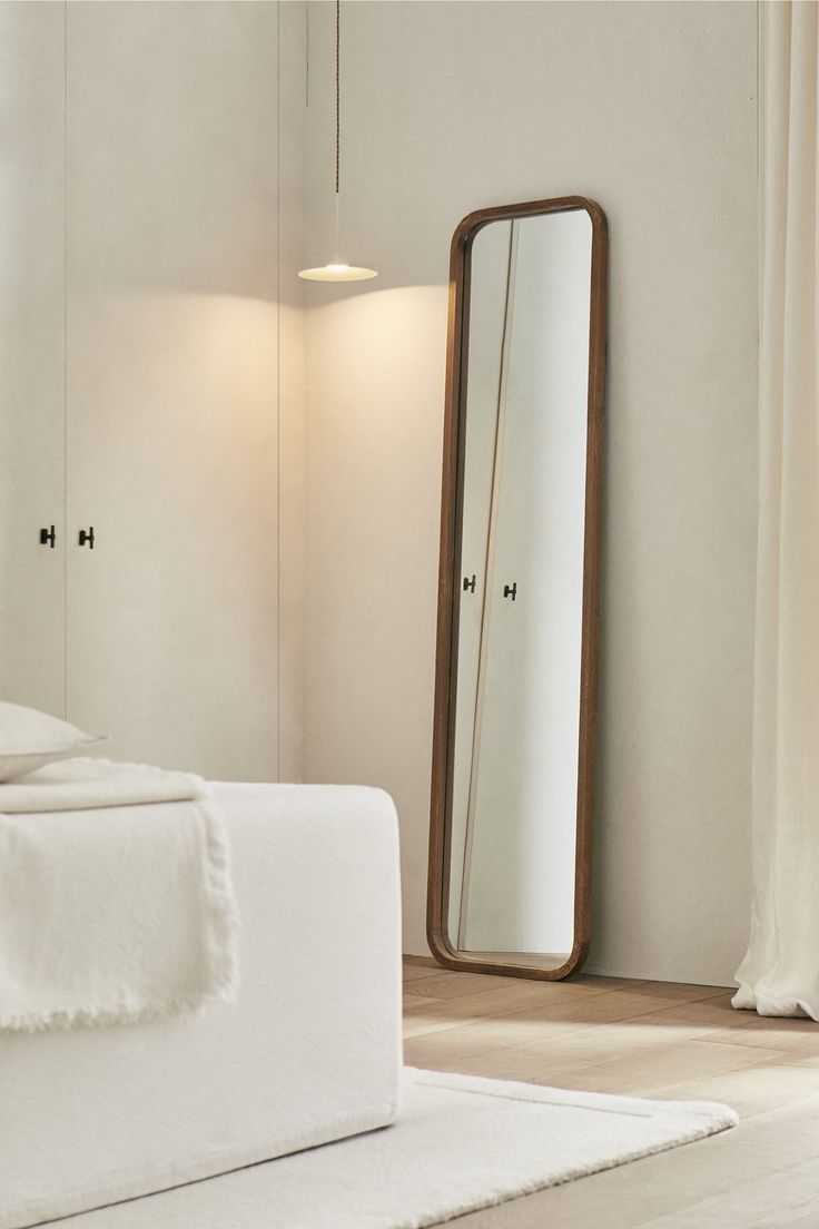 a white bed sitting next to a tall mirror