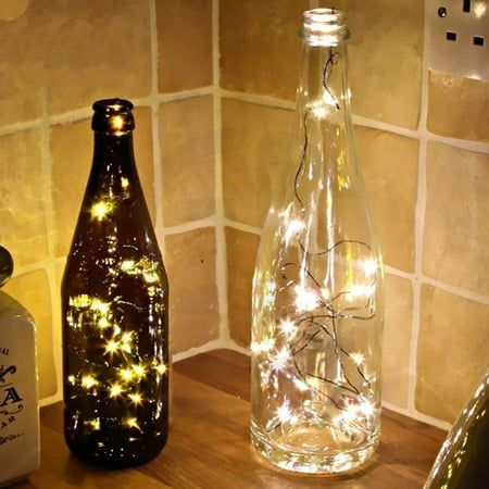 two bottles with lights in them sitting on a counter