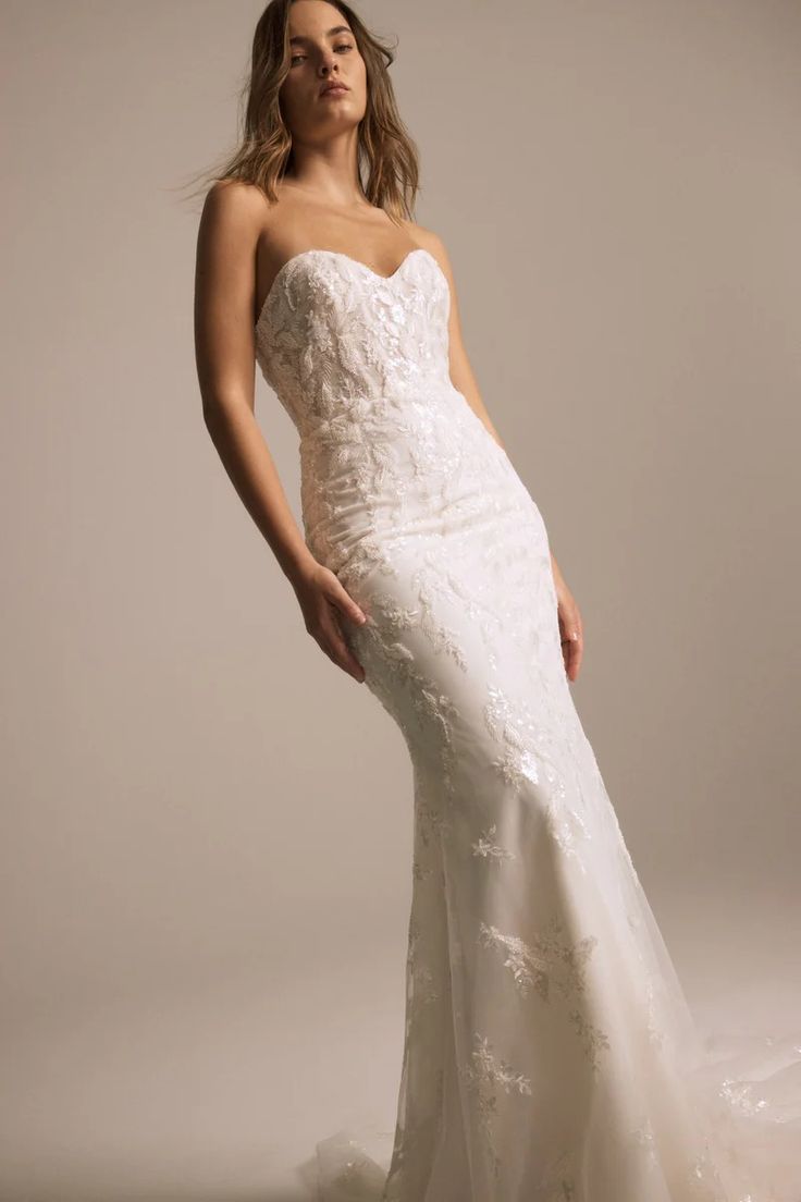 a woman in a wedding dress posing for the camera with her hands on her hips