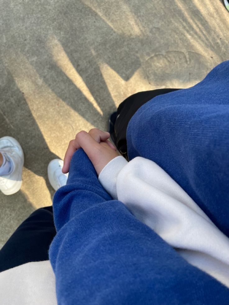 two people holding hands while sitting on a bench with their feet propped against each other