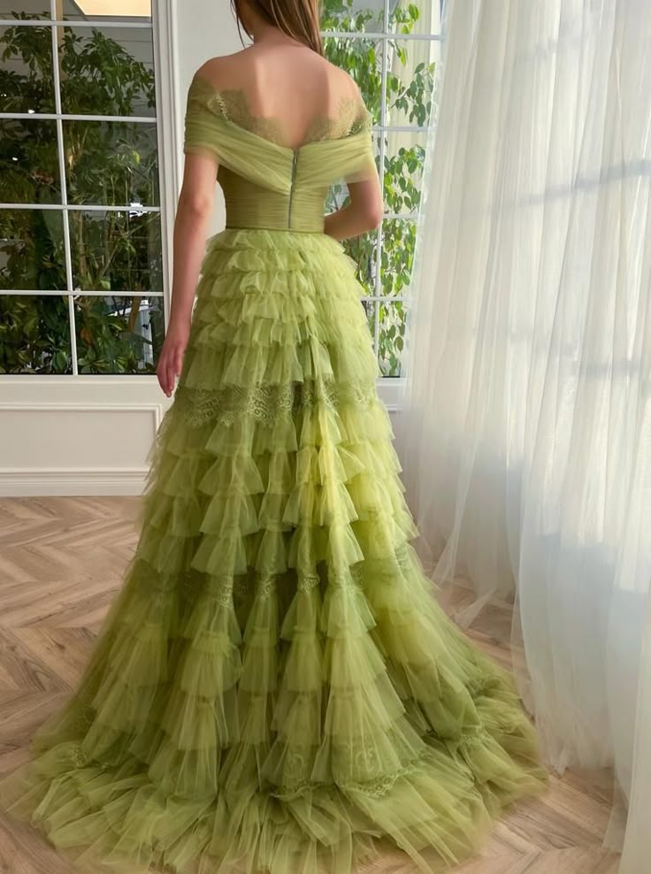 Discover our Verdant Enchantment Gown, a perfect blend of sophistication and whimsy. This captivating gown features a soft, delicate fabric adorned with a patterned lime green tulle. The off-shoulder neckline and draped wrap bodice create a flattering silhouette, while the cinched waist and decorative ribbon belt accentuate your figure. Experience the enchanting ball-gown silhouette with a floor-length skirt, ideal for any formal occasion. Make a lasting impression in this stunning piece that ex Enchanted Gown, Green Hand-embellished Wedding Gown, Teuta Matoshi Green Dress, Green Floor-length Tulle Dress, Green Tulle Floor-length Evening Dress, Green Tulle Floor-length Ball Gown, Tea Length Prom Dress, Dream Prom, Green Tulle