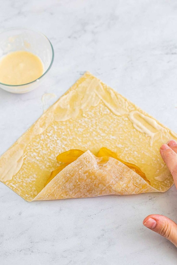 someone is making a pastry with butter on the top and in the background, there are other ingredients to make it