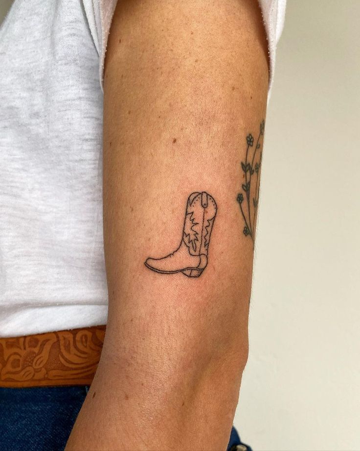 a woman's arm with a tattoo on it that has a cowboy boot and flowers