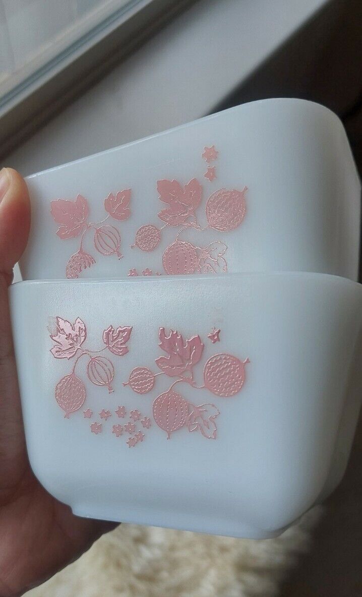 two white dishes with pink designs on them are being held by someone's hand