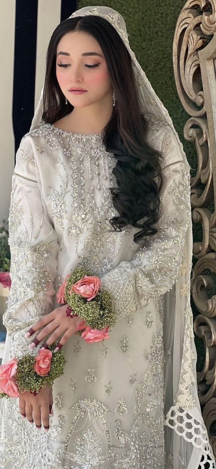 a woman standing in front of a mirror wearing a white dress with flowers on it