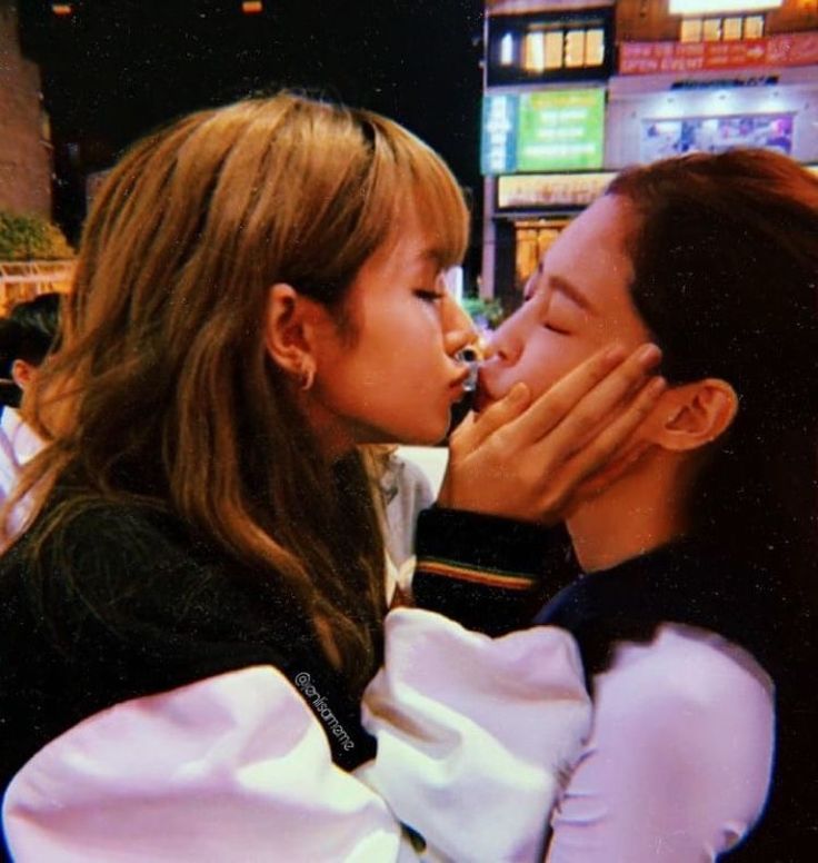 two young women kissing each other on the street